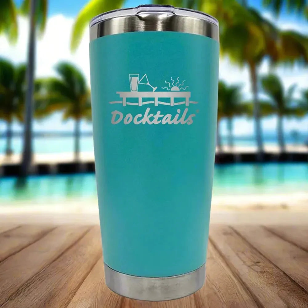 A turquoise insulated travel tumbler with a stainless steel lid and base, featuring an engraved graphic of a dock and the word 'Docktails' on the front, set against a blurred tropical beach background.