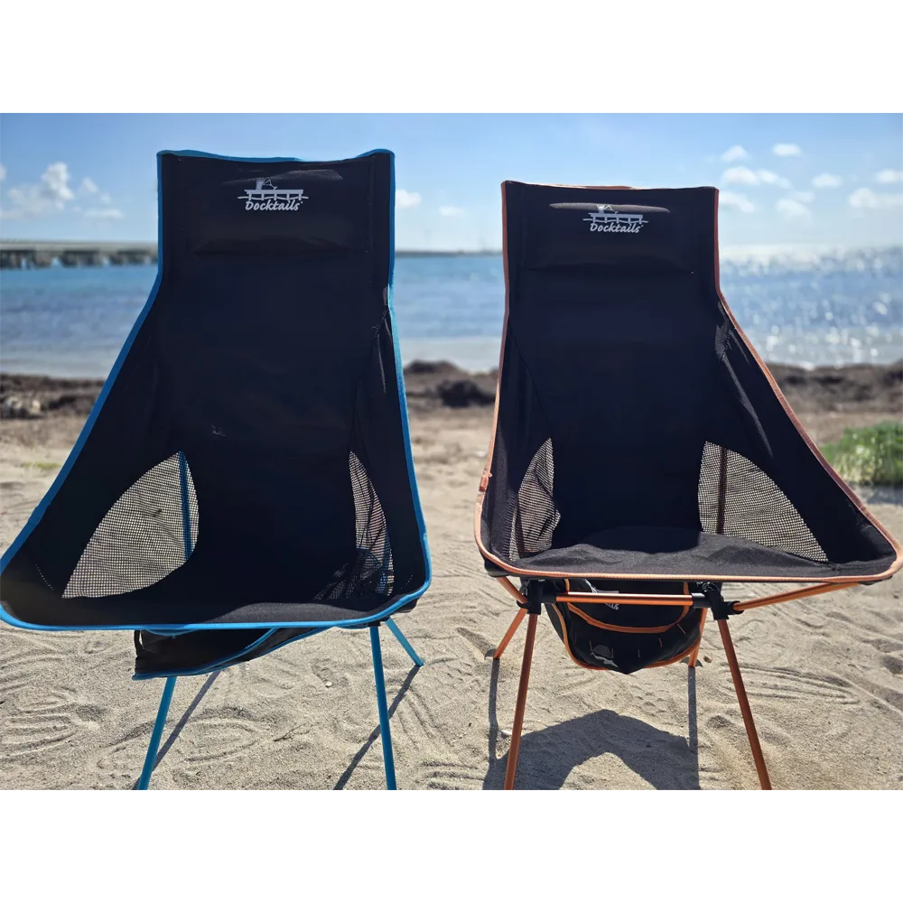Two portable chairs on a sandy beach with water and sky in the background