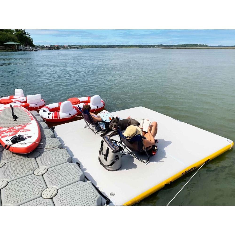 Solstice inflatable dock with two people in chairs sitting on it and a dog with them