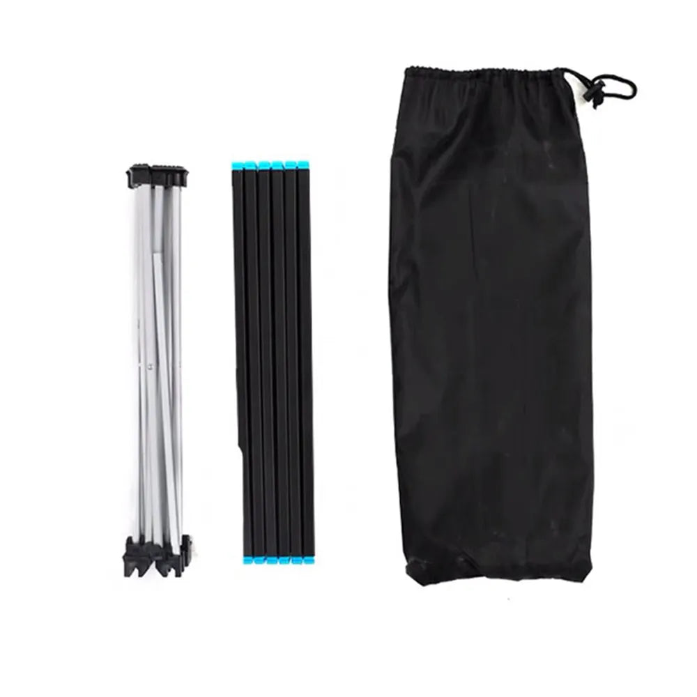 A set of three items on a plain white background: a folded silver-and-black set of table legs on the left, a folded black slatted table top with small blue end caps in the center, and a black drawstring storage bag on the right.