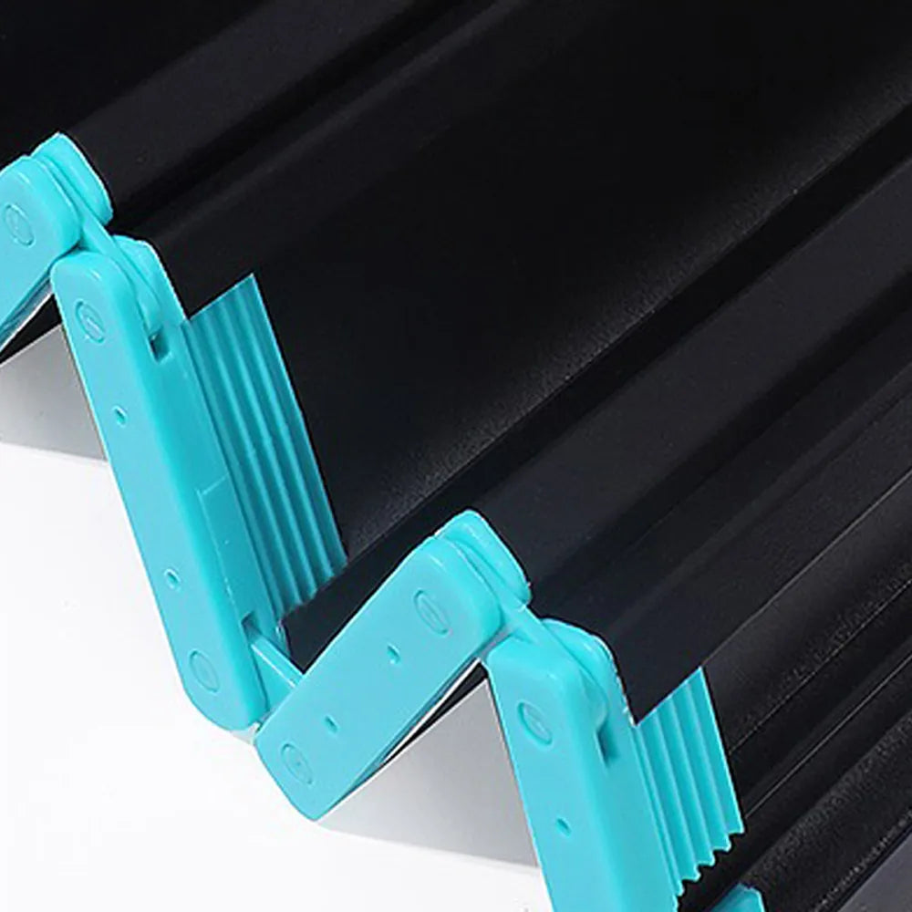Close-up of a black expandable folding table with bright turquoise plastic corner guards and support arms, shown on a white surface.