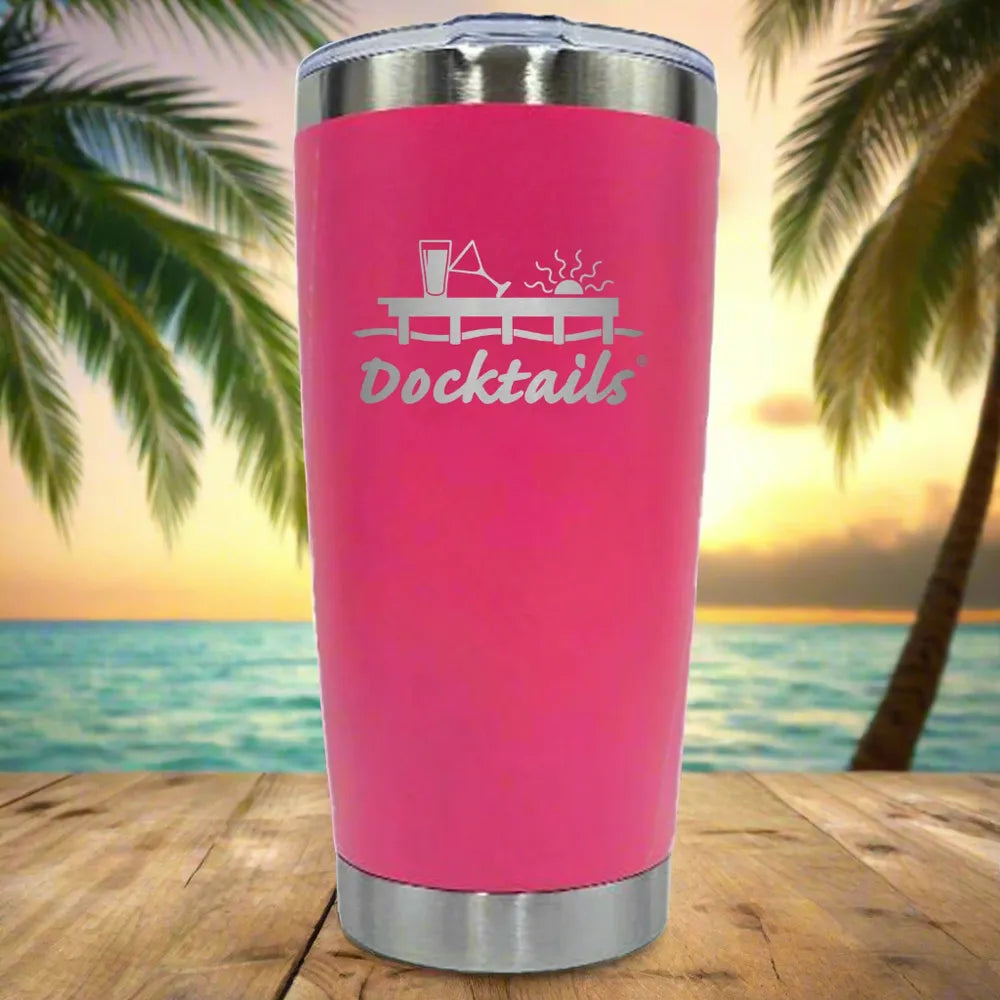 A bright pink insulated tumbler with stainless steel rim and base, featuring an engraved 'Docktails' graphic with a cocktail glass and drink illustration, set against a tropical beach sunset background with palm trees.